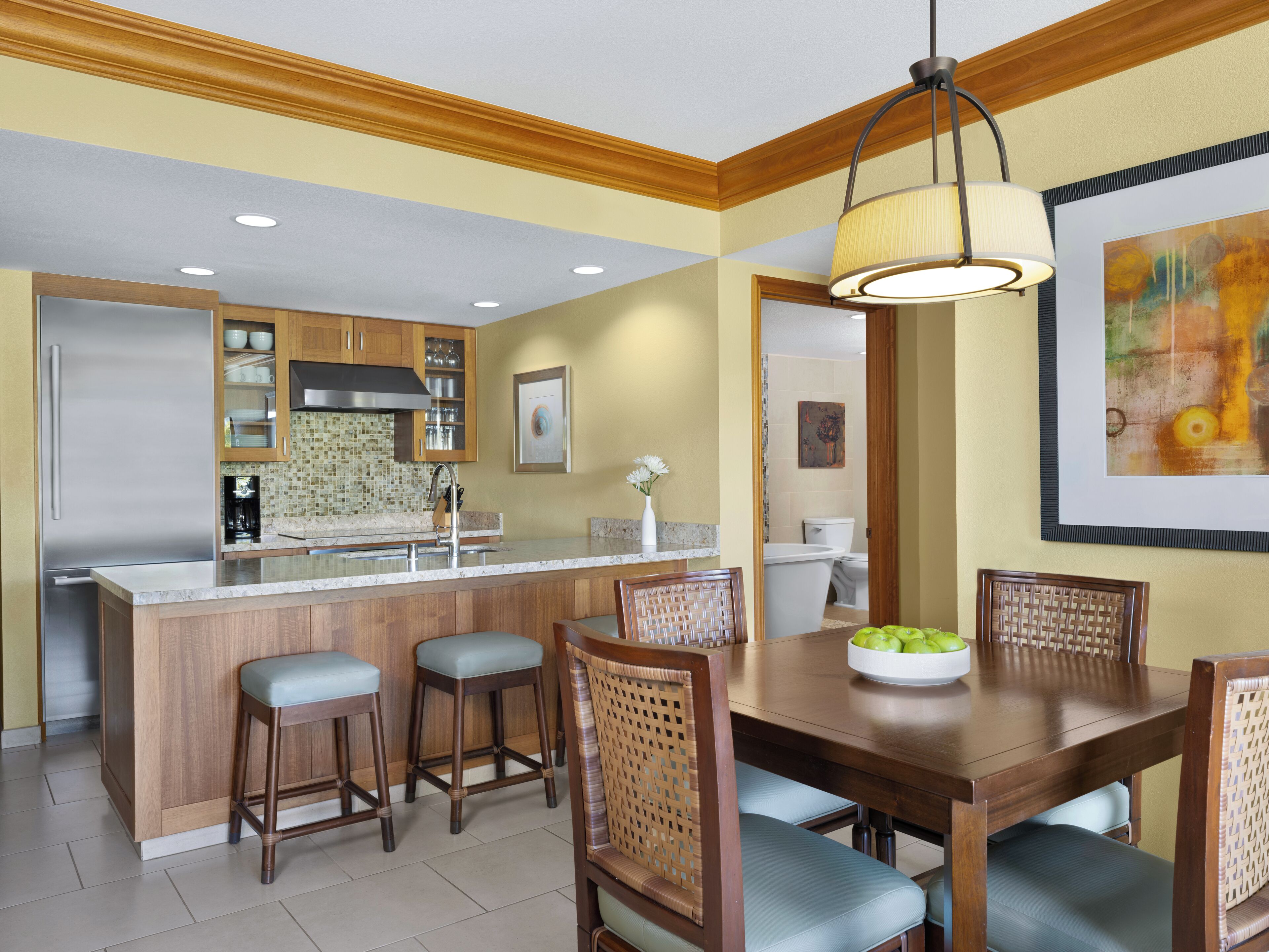 Una cocina moderna con una isla central, taburetes de bar de madera y una mesa de comedor con sillas.
