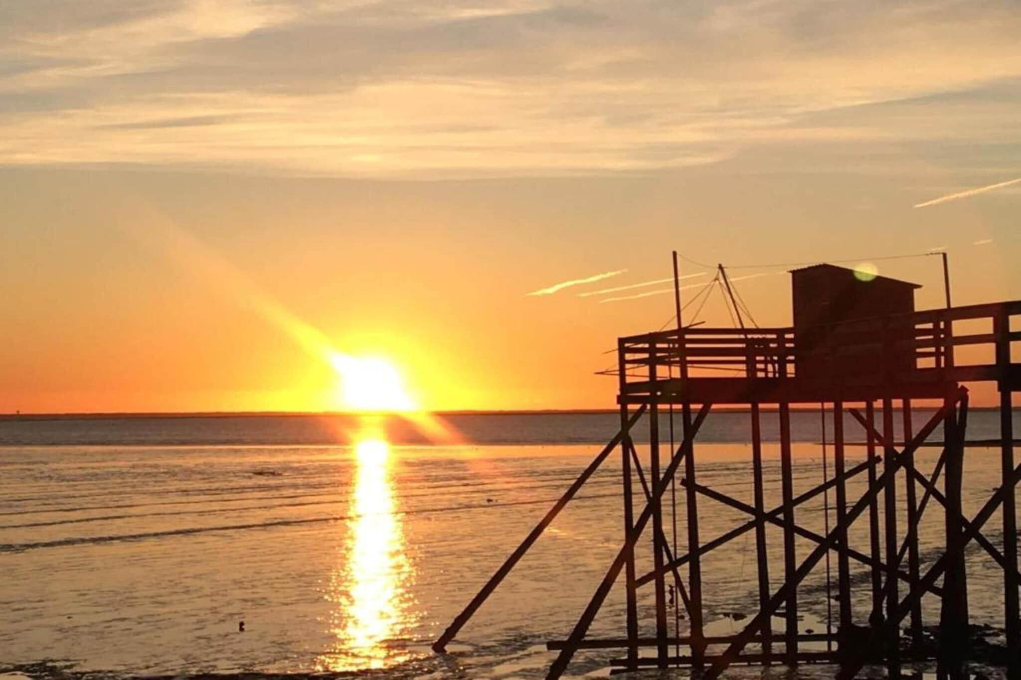 Laiturirakennelma, josta avautuu näkymä auringonlaskuun veden yllä.
