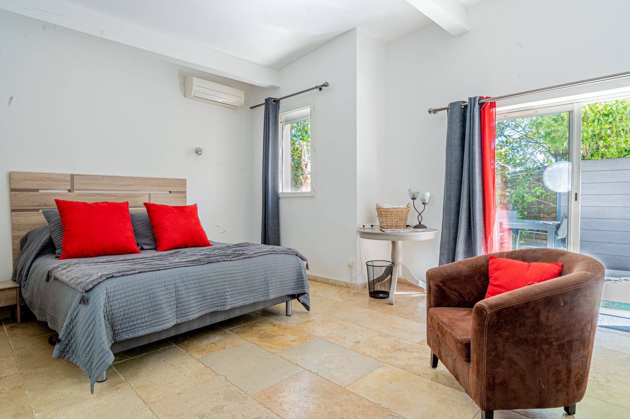 Une chambre avec un lit, une chaise, une petite table et une fenêtre.