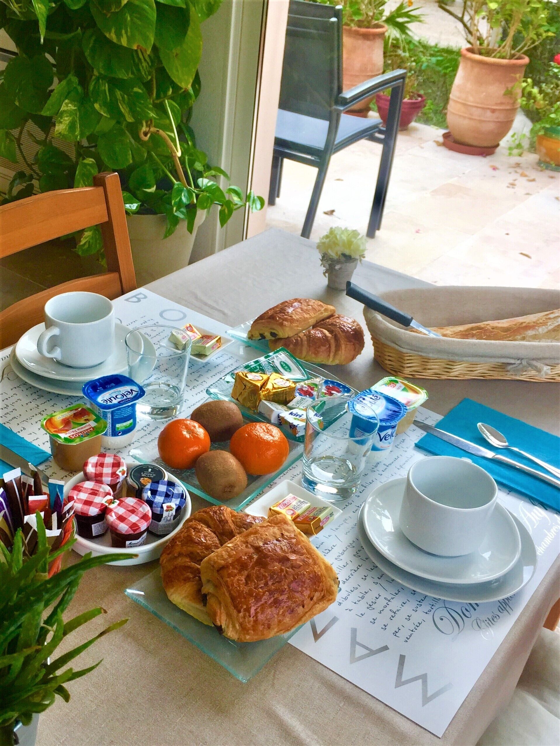 Une table de petit-déjeuner avec des croissants, des oranges, du yaourt et un menu.
