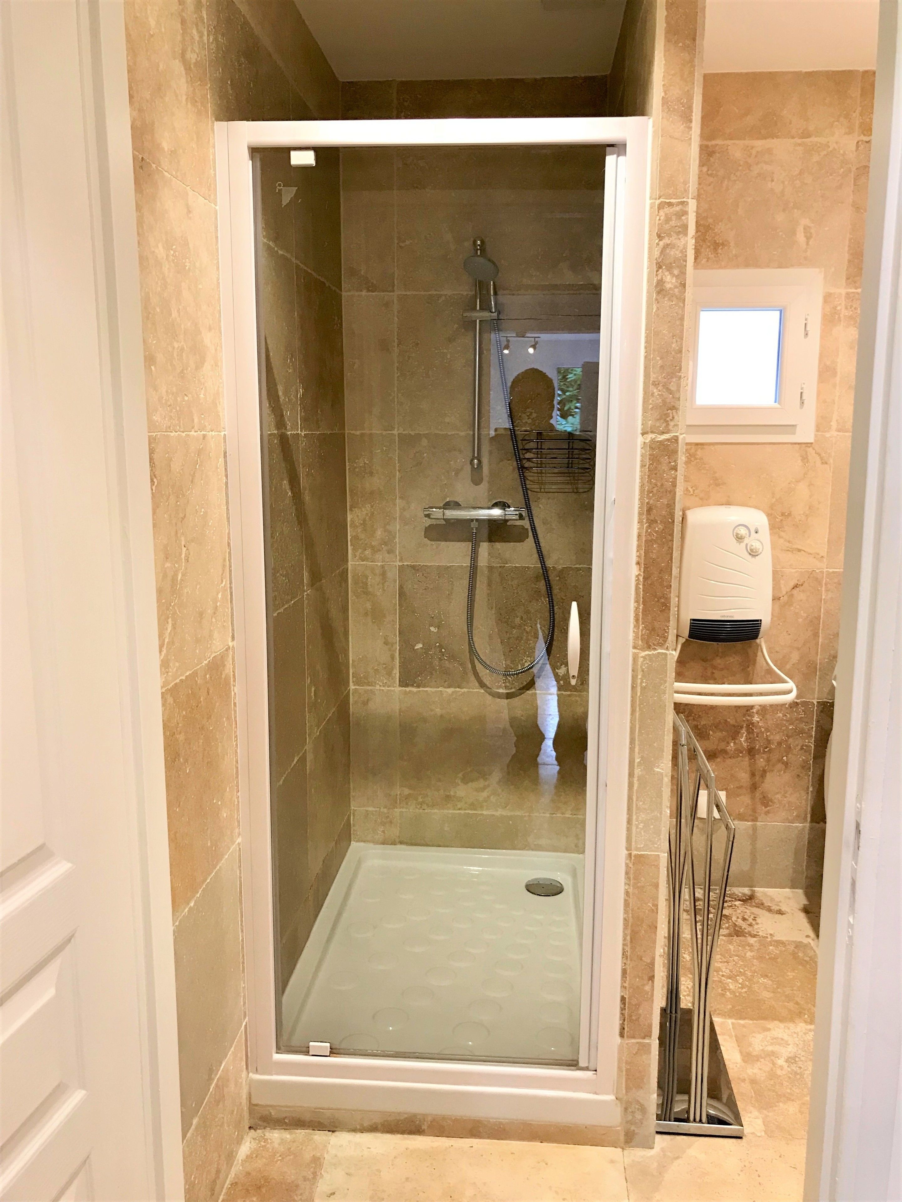 A glass-enclosed shower stall with a handheld showerhead and a handheld shower attachment.