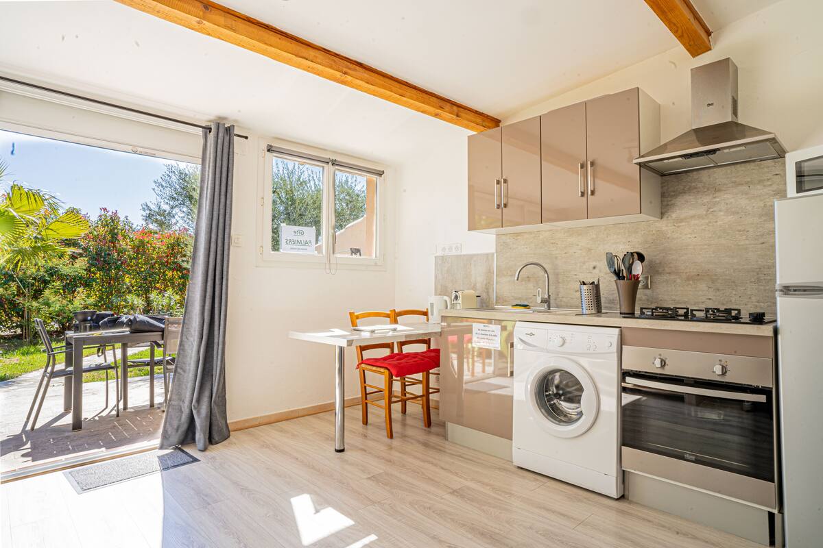 A modern kitchen with a washing machine, oven, and dining area with a table and chairs.