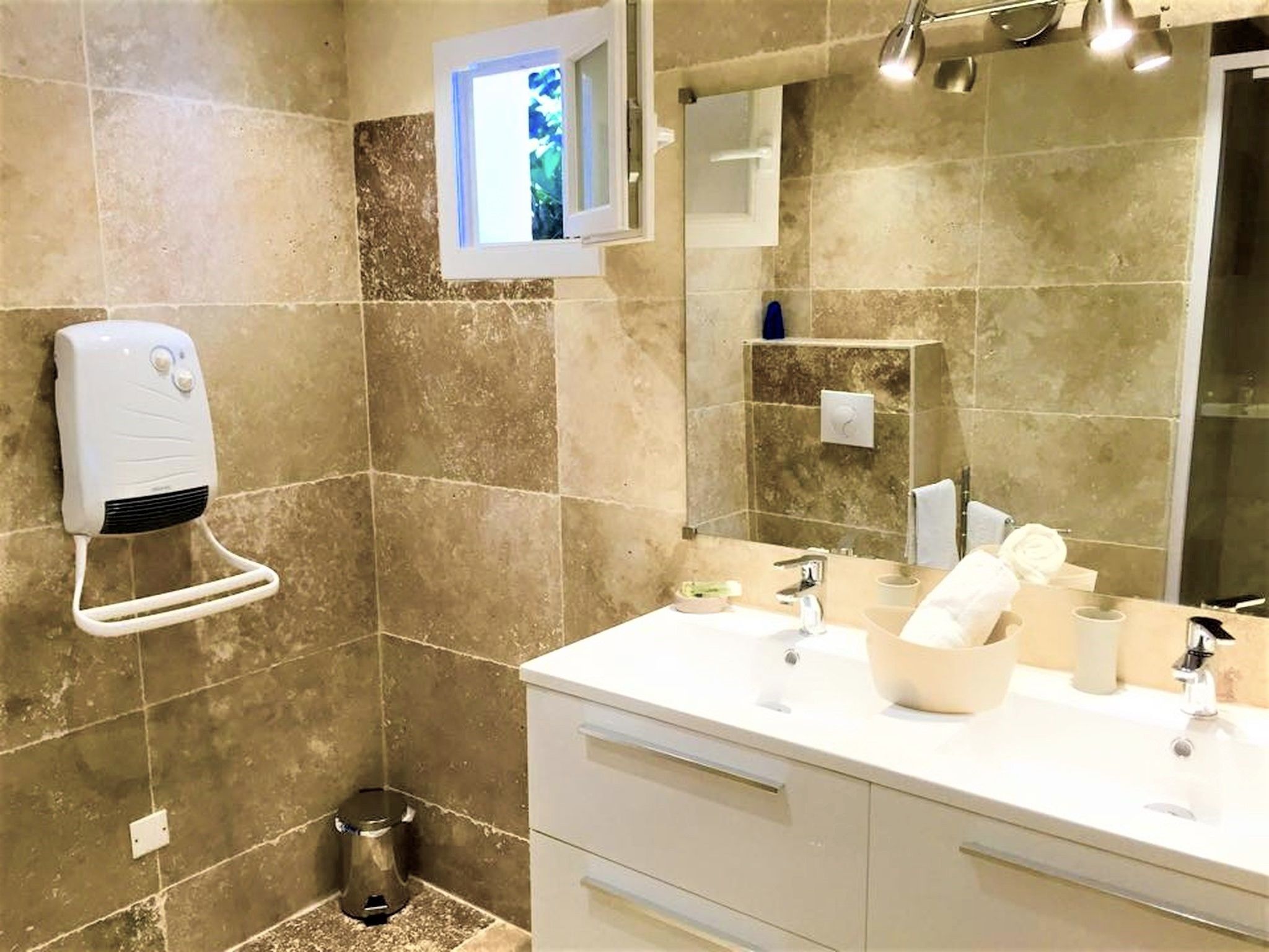A bathroom with a large mirror, a towel rack, a hand dryer, and a sink with a mirror above it.