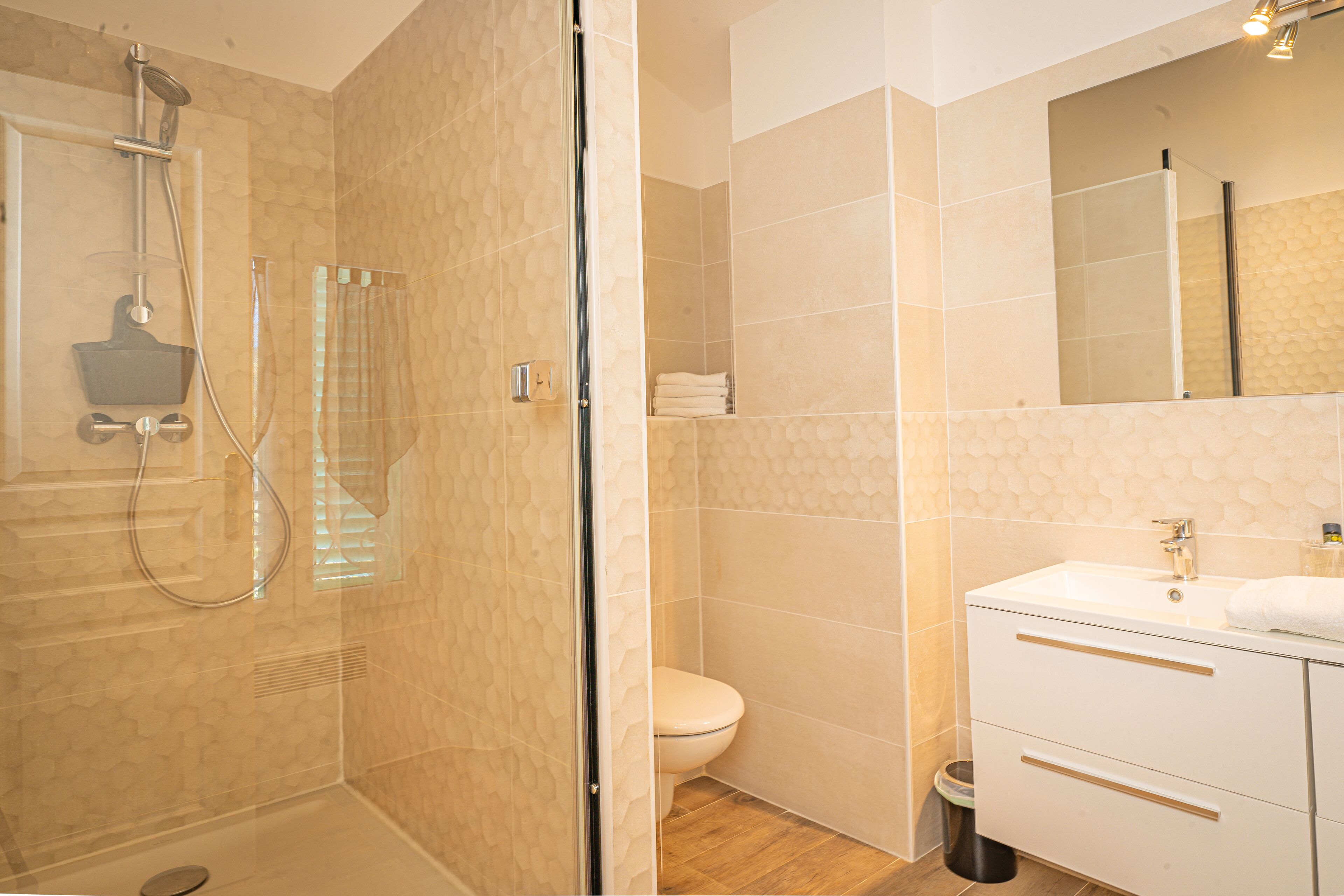 A modern bathroom with a glass-enclosed shower, a white sink, and a toilet.