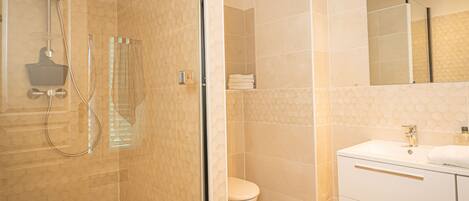 A modern bathroom with a glass-enclosed shower, a white sink, and a toilet.