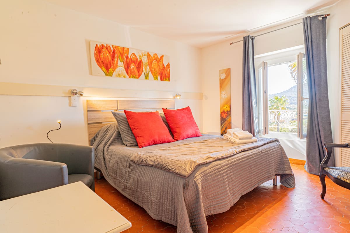 A bedroom with a bed, a chair, a table, and artwork on the walls.
