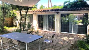 A patio area with a table and chairs, a covered seating area, and a sliding glass door leading to a covered outdoor space.