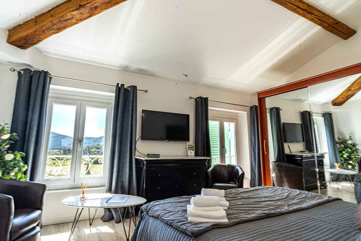 A hotel room with a bed, a TV, a desk, and a view of the outdoors.