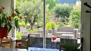 Una habitación con puerta de cristal corredera que da a un patio exterior con muebles de mimbre y plantas en macetas.