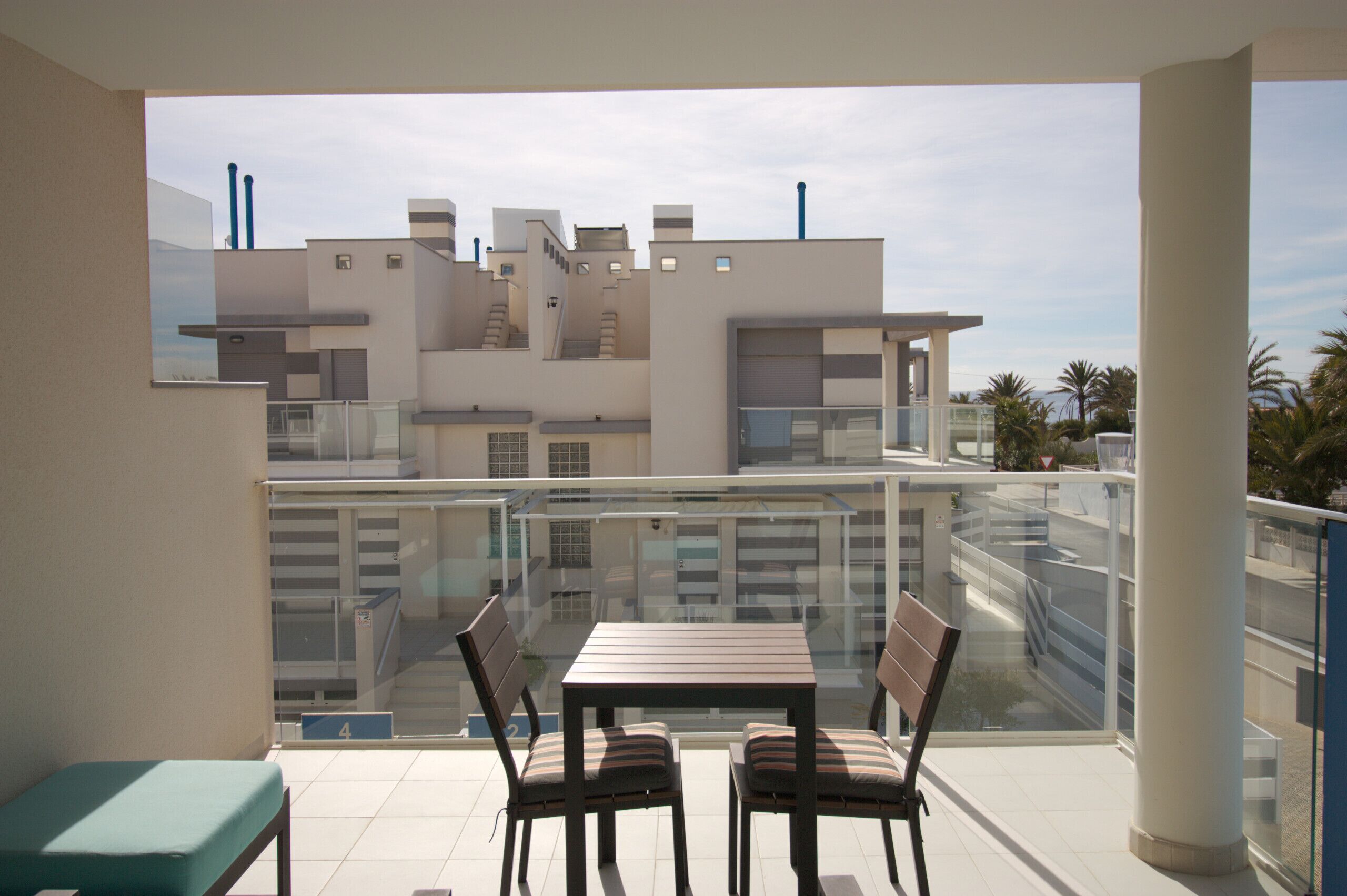 A balcony with a table and chairs, a bench, and a view of modern buildings.