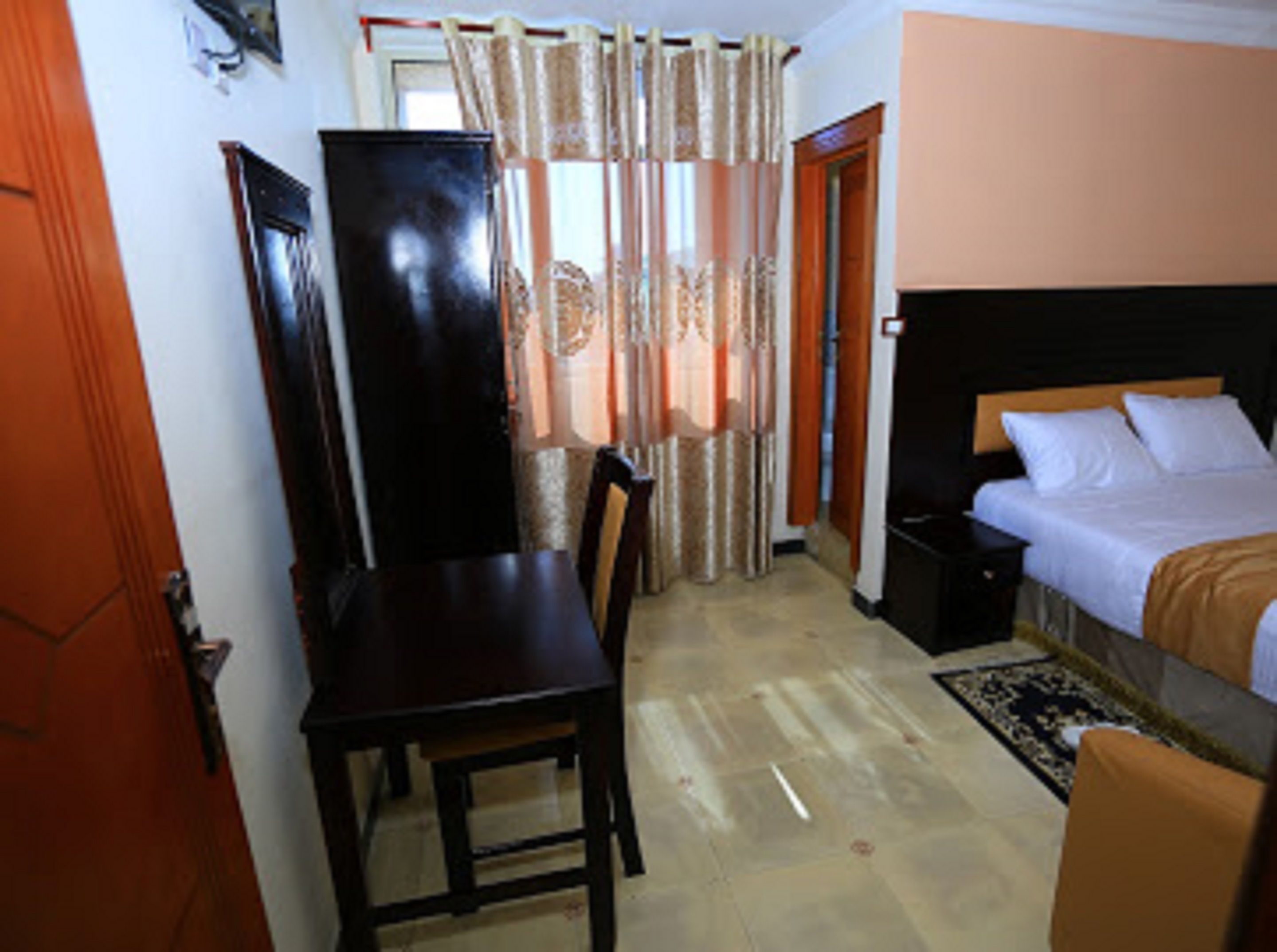 Una habitación de hotel con cama, escritorio, silla y armario.