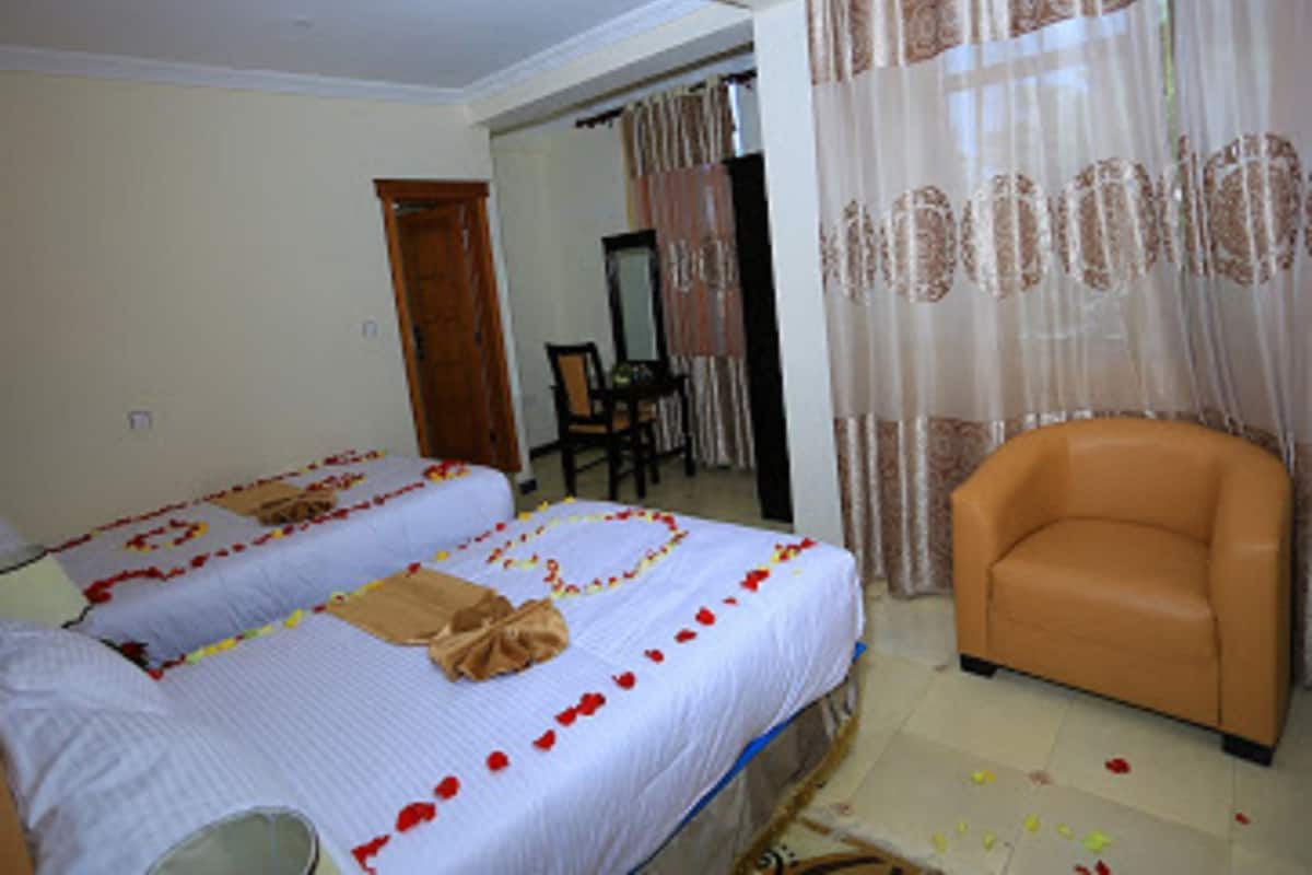 A hotel room with two beds, a chair, and a mirror.