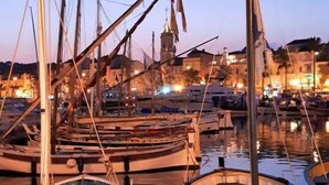 A marina with several boats docked, a church with a bell tower in the background, and a clear sky.