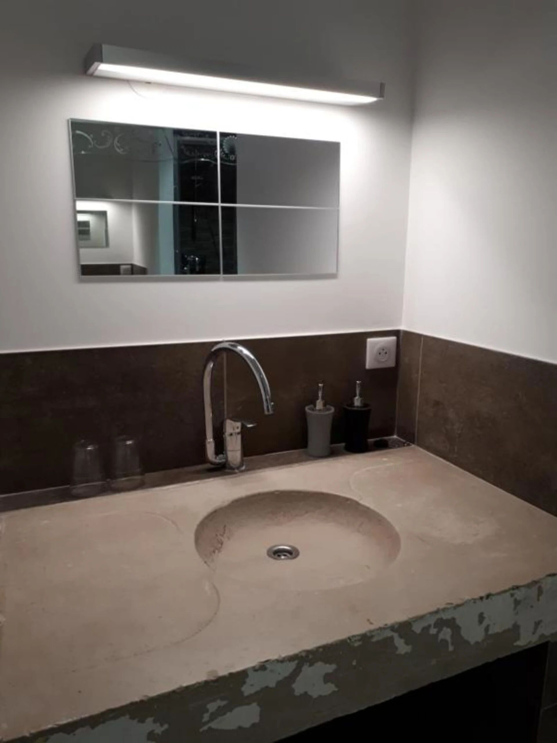 Un bagno con lavandino, specchio e un lampadario a parete.