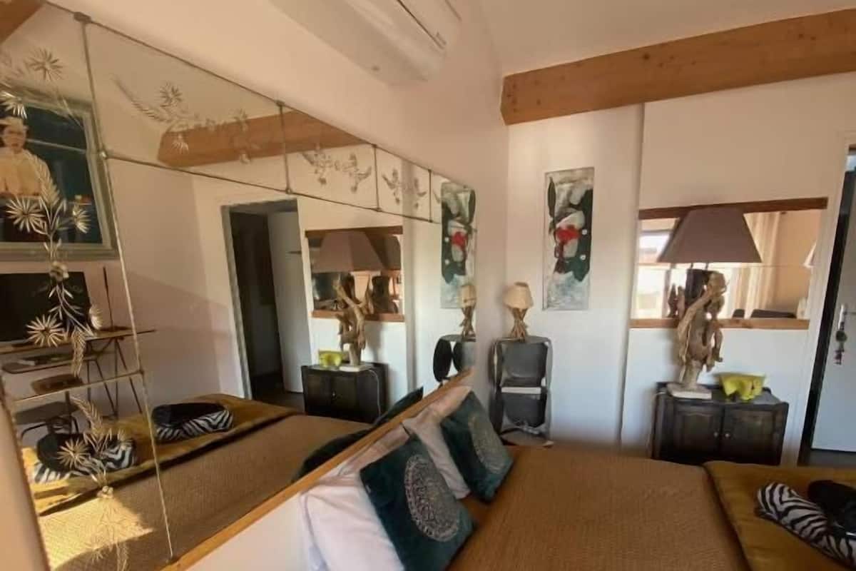 Ein Schlafzimmer mit einem großen Bett, einem Spiegel und einer Holzbalkendecke.