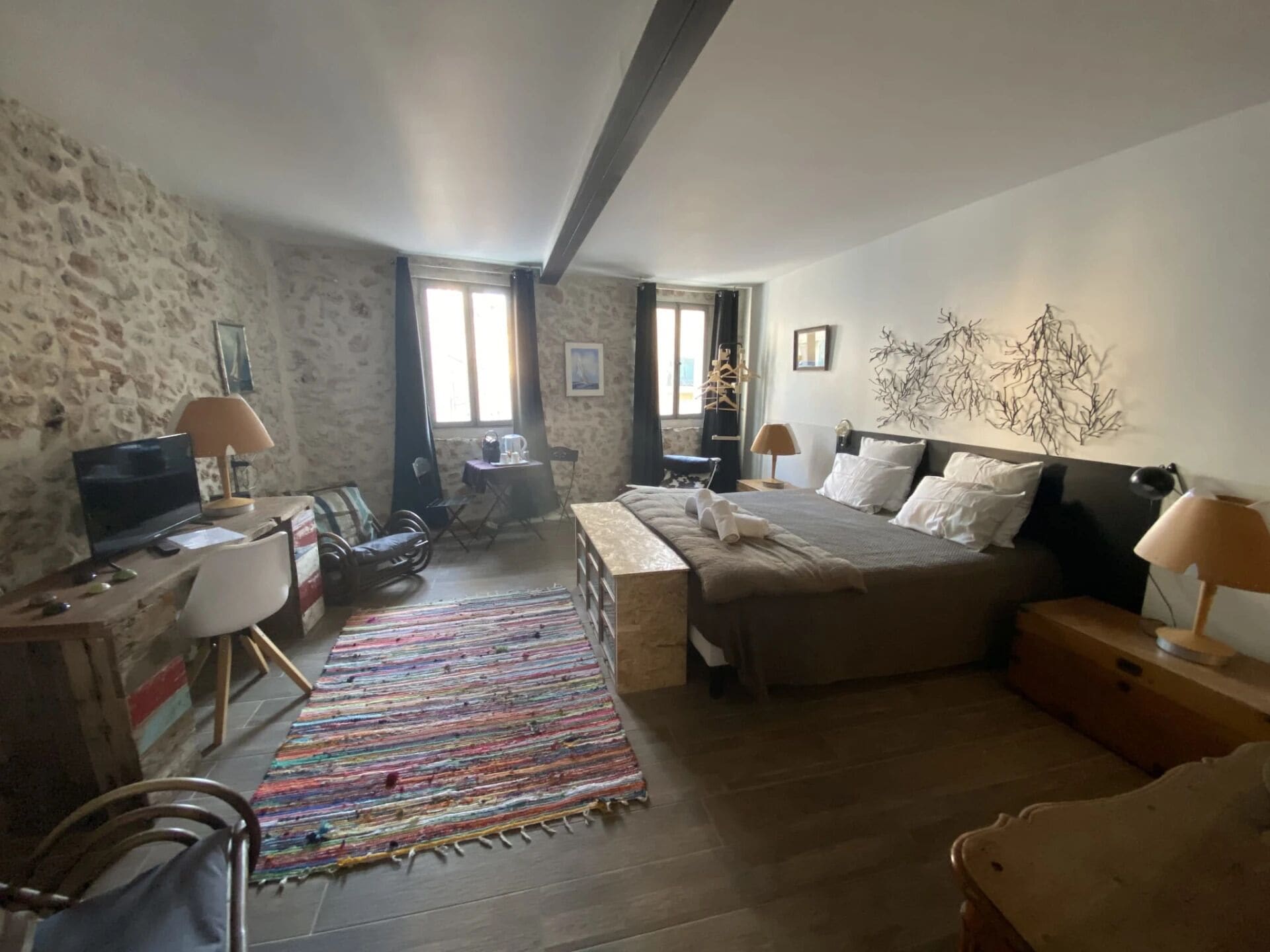 Un dormitorio con una cama, un escritorio con computadora, una silla, una alfombra y una ventana.