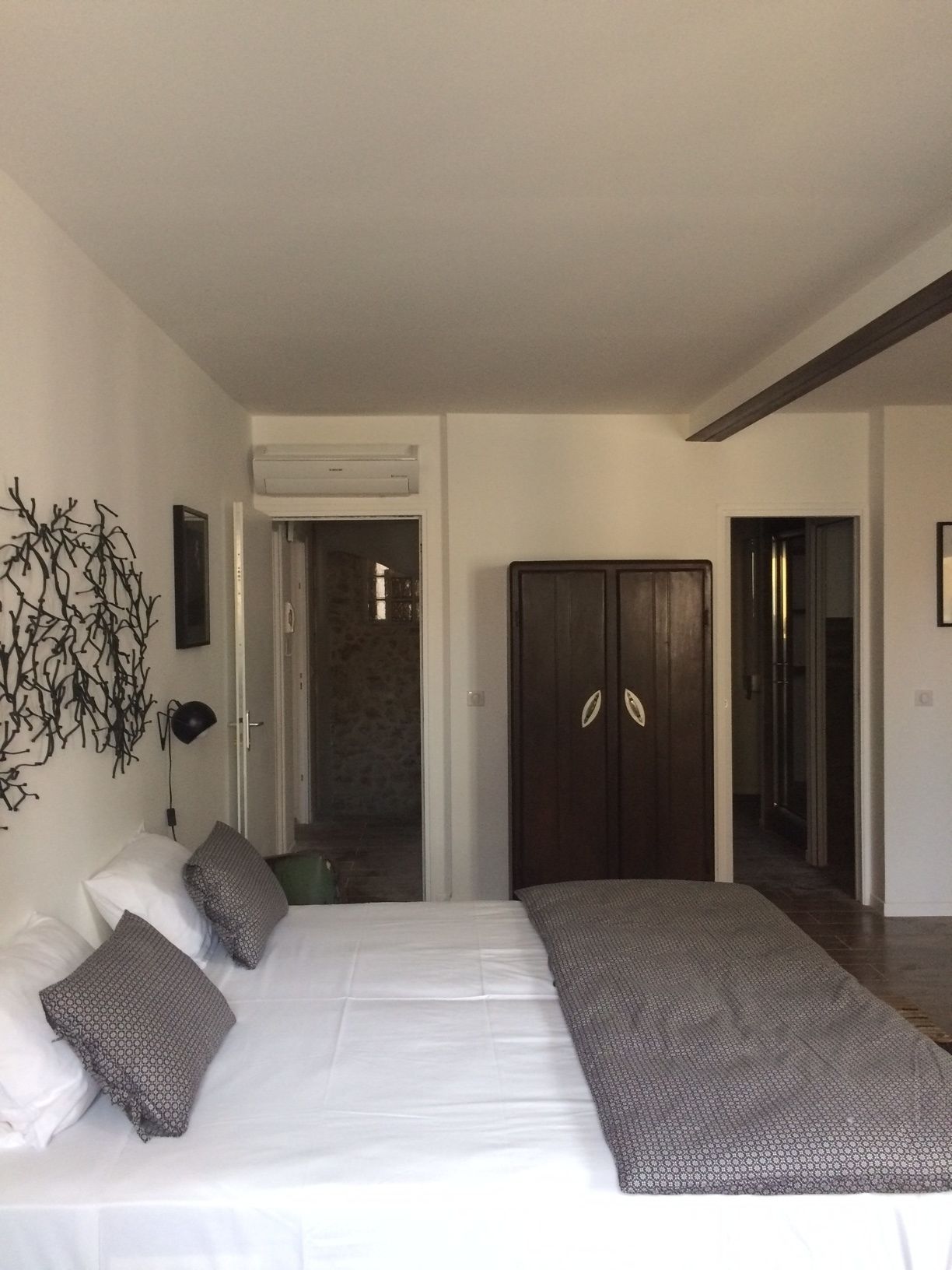 Un dormitorio con una cama grande, un armario y una puerta que da a otra habitación.