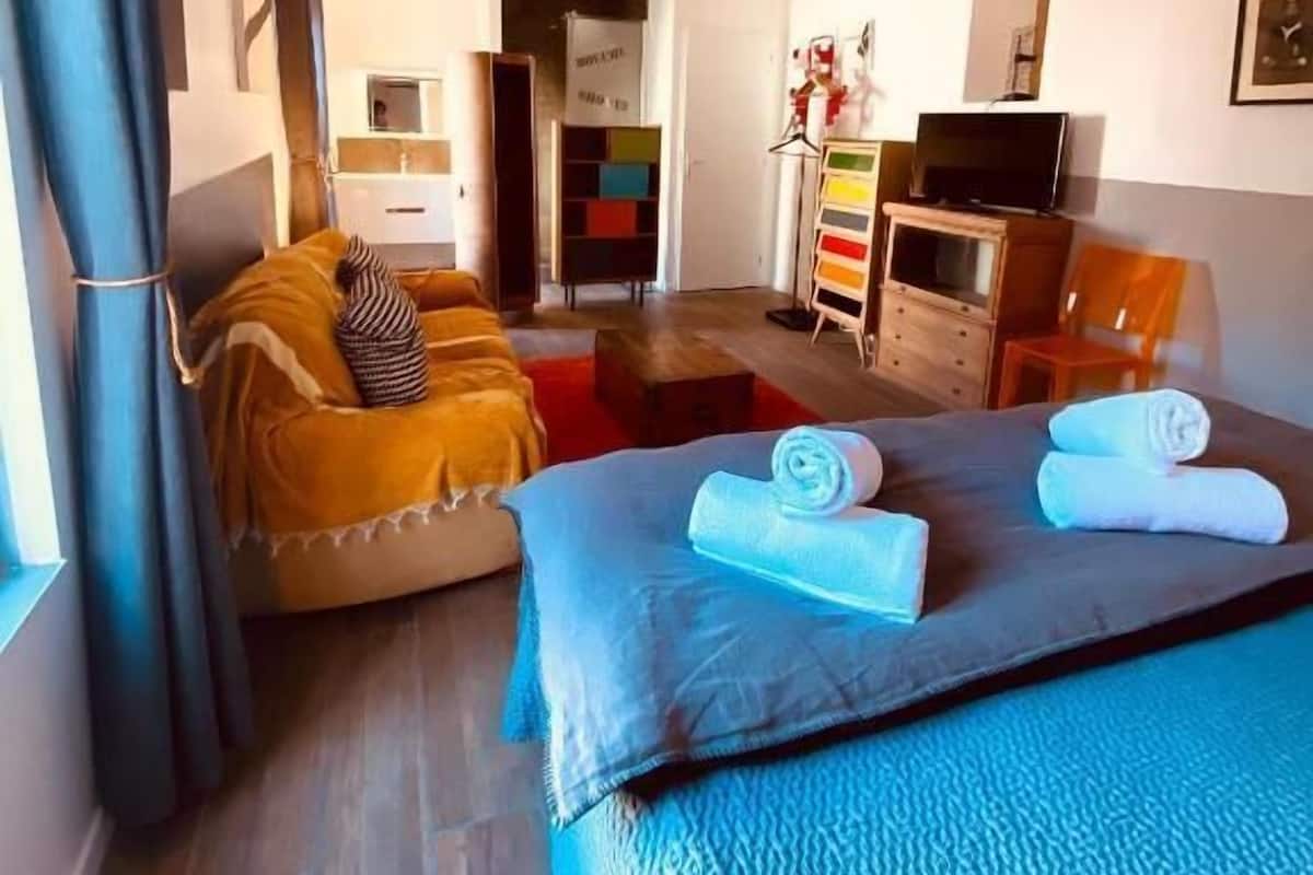Ein Hotelzimmer mit Bett, einer Couch, einem Fernseher, einem Schrank und einem sichtbaren Badezimmer im Hintergrund.