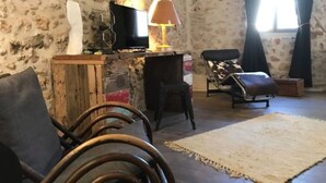 A living room with a rustic aesthetic, featuring a wooden entertainment unit, a sofa, a patterned rug, and a chair with a cowhide design.