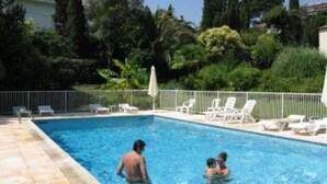 Une piscine avec des chaises longues et un espace délimité par une clôture.