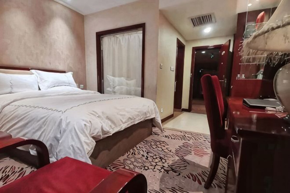 Una habitación de hotel con cama, escritorio, silla y espejo.