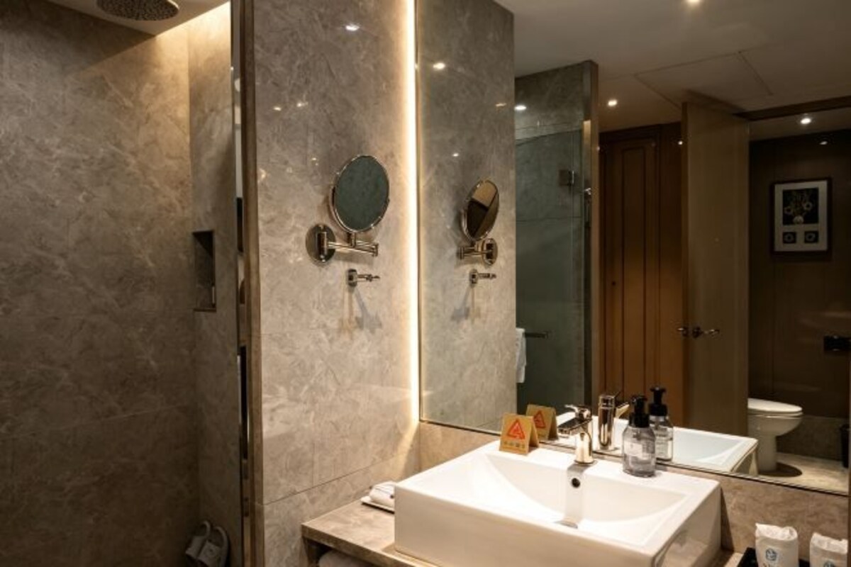 Un baño moderno con un espejo grande, dos lavamanos y una zona de ducha.