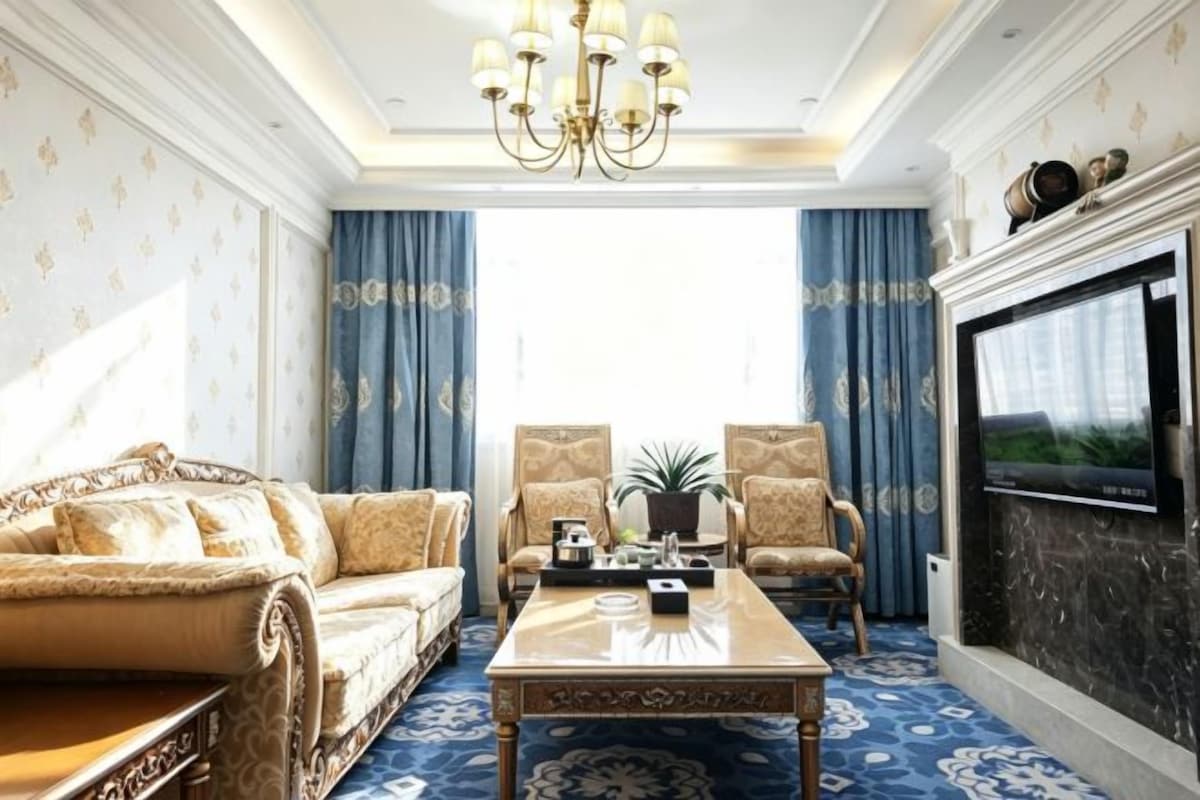 A luxurious living room with a sofa, armchairs, a coffee table, and a fireplace.
