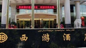 A hotel with a sign reading "West Tour Hotel" and a large golden emblem on the facade. - West Tour Hotel (Shanshan)