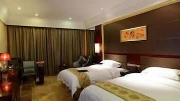 A hotel room with two beds, a desk, a chair, and a painting on the wall.