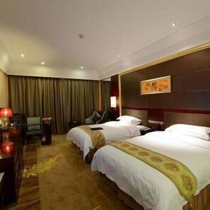 Een hotelkamer met twee bedden, een bureau, een stoel en een schilderij aan de muur.