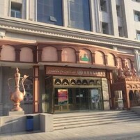 Un edificio de estilo arquitectónico tradicional, con ventanas en arco y una entrada central con escalones ascendentes.