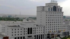 A large, multi-story building with a central tower and symmetrical facade. - West Tour Hotel (Shanshan)