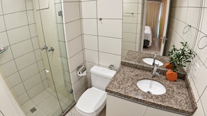 A bathroom with a glass shower enclosure, a toilet, and a sink with a granite countertop. - Beach Class Fortaleza Praia de Iracema (Fortaleza)