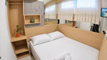 Habitación de hotel moderna con una cama grande, armario empotrado, una planta pequeña y un televisor.