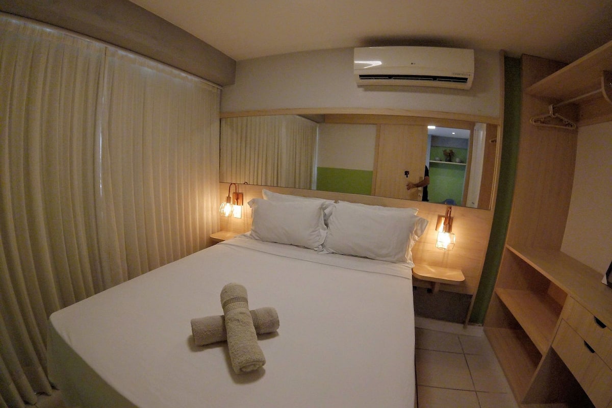 Une chambre d’hôtel équipée d’un lit, d’une table de chevet, d’un miroir, d’un climatiseur et d’une armoire.