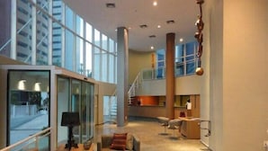 Een ruime lobby met een hoge plafond, grote ramen en een modern interieur.