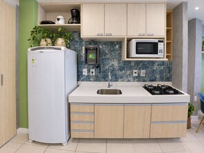 Een moderne keuken met een inbouwkoelkast, een magnetron, een gasfornuis en een spoelbak.