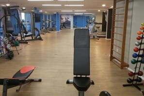 Een sportschool met diverse fitnessapparaten, waaronder loopbanden, hometrainers en krachtapparaten.