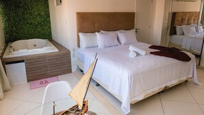 Een hotelkamer met een groot bed, een aparte badkamer met bad en een klein tafeltje met stoel.