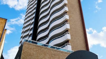 Um edifício alto com fachada curva e varandas.