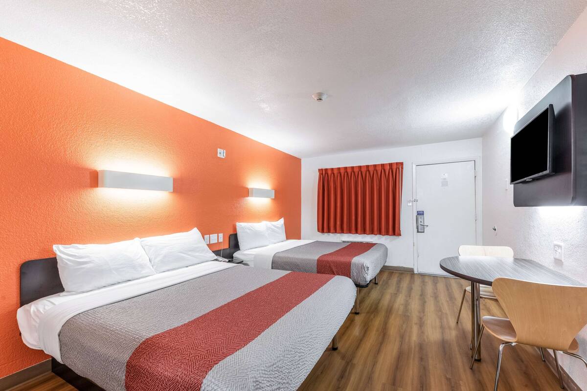 Ein Hotelzimmer mit zwei Betten, einem Esstisch und einem Fernseher.