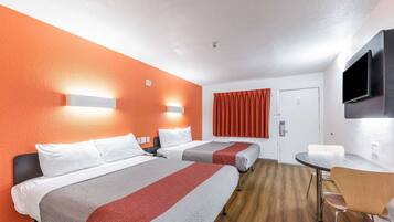 A hotel room with two beds, a dining table, and a TV.