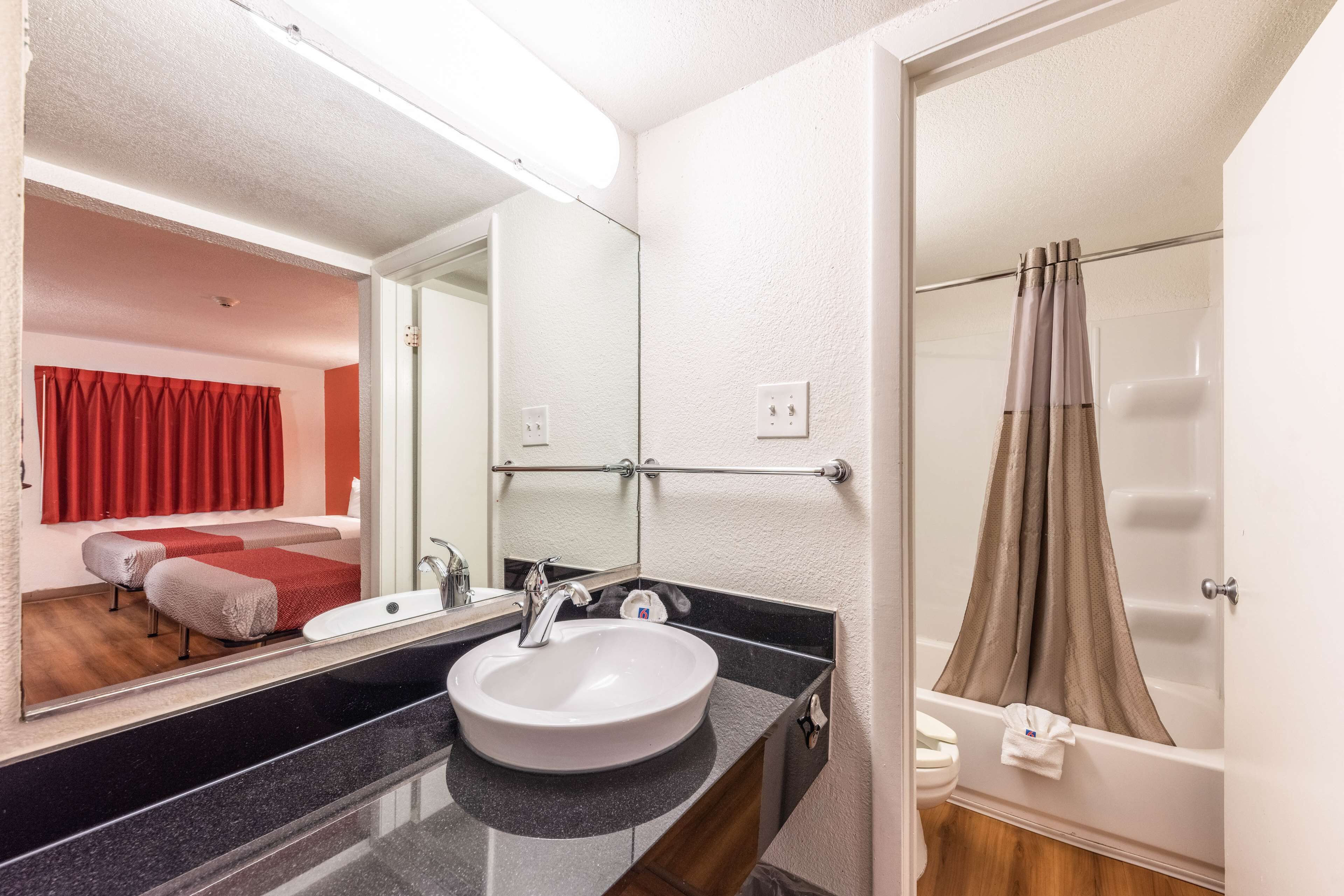 Un baño con lavamanos blanco, espejo y cortina de ducha.