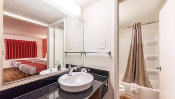 Un baño con lavamanos blanco, espejo y cortina de ducha.