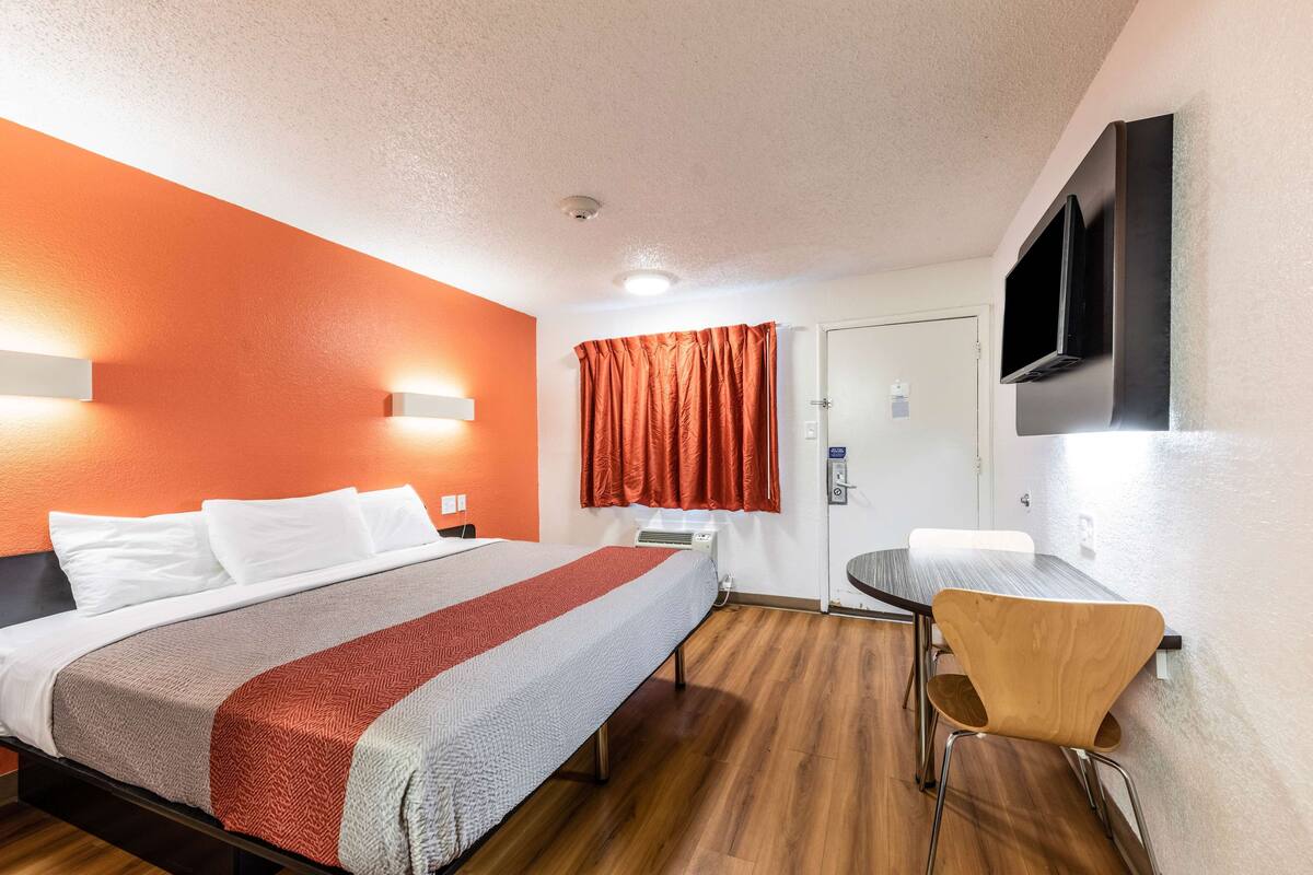 Ein Hotelzimmer mit einem Bett, einem Schreibtisch, einem Stuhl, einem Fernseher und einer Tür.