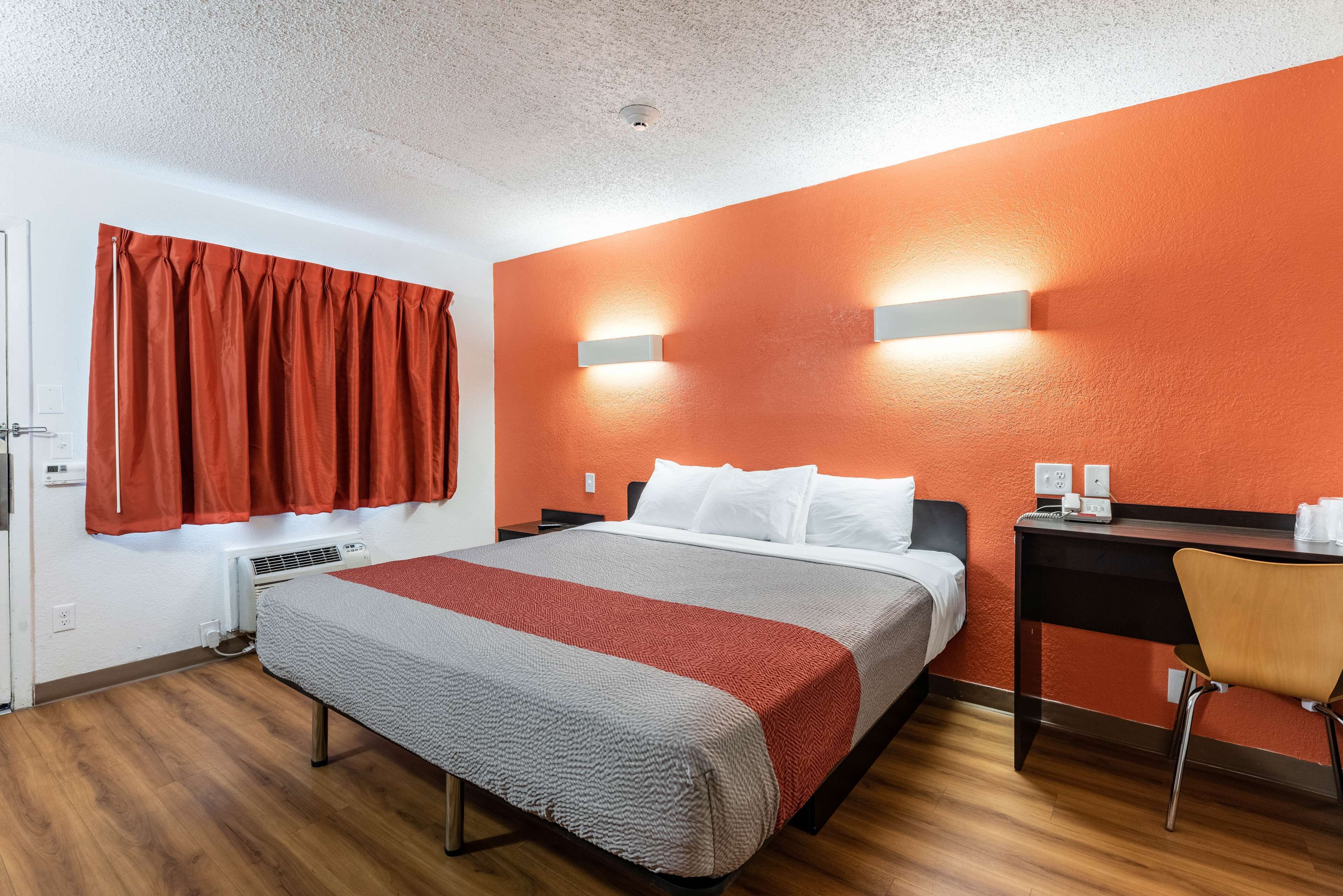 A hotel room with a bed, a desk, and a chair.