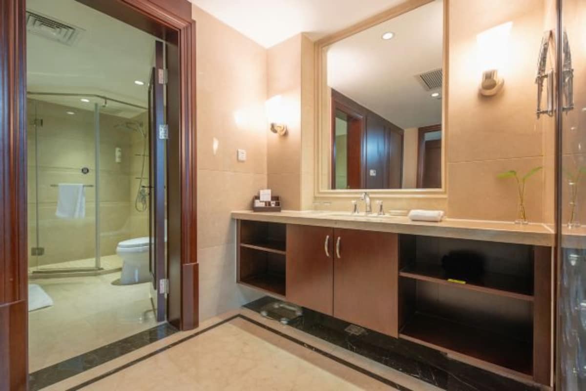 Uma casa de banho moderna com cabine de duche em vidro, um espelho grande e uma toucador com bancada de mármore.