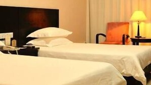 A hotel room with two single beds, a nightstand with a lamp, and a painting on the wall. - Hailan Hotel (Wuxi)