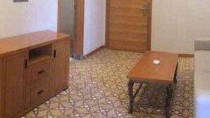 A room with a wooden cabinet, a small table, and a patterned floor. - Hailan Hotel (Wuxi)