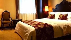 A hotel room with a large bed, a chair, a nightstand, and a window with curtains. - Hailan Hotel (Wuxi)